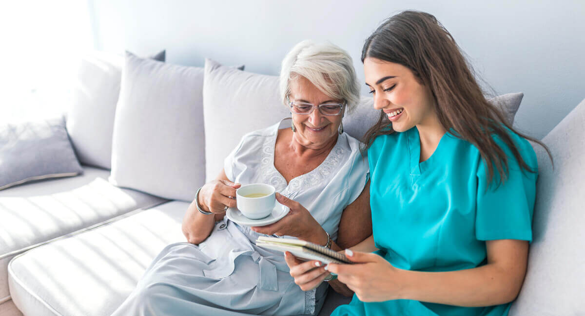 A respite care worker assisting a senior woman in reading a book