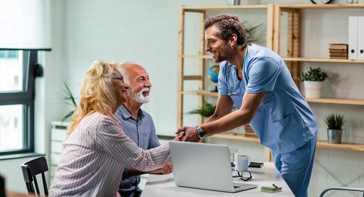 A nurse extends a warm handshake to grateful parents showing their trust.