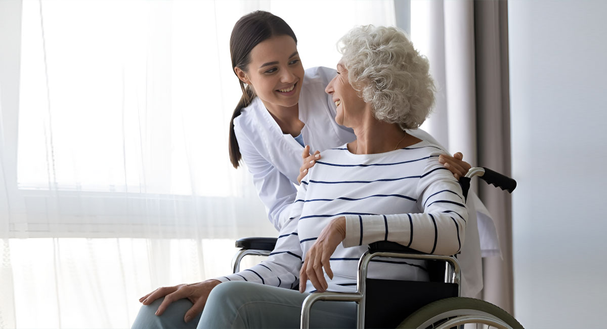 A caregiver speaking with an elderly woman at her residence