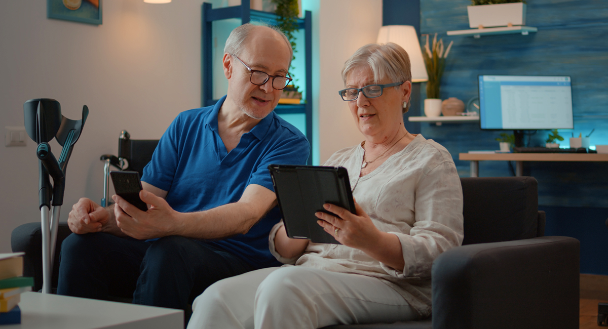 An elderly couple using phone to at home, enjoying technology in free time