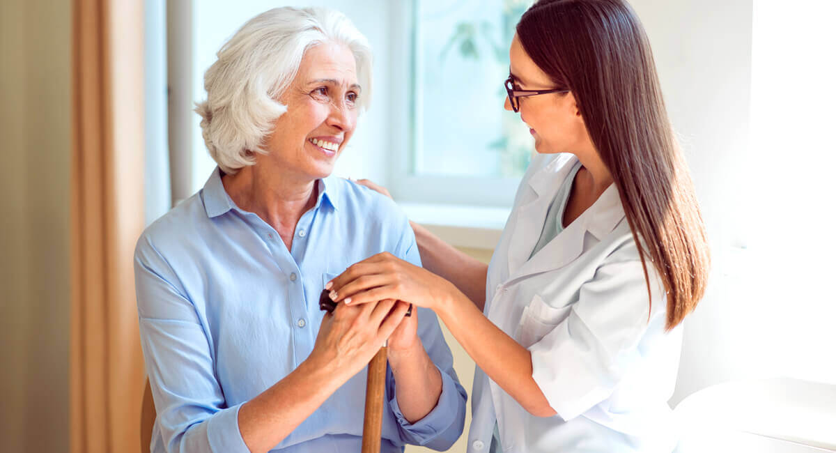 A senior woman is accompanied by a live-in carer to help with daily chores.