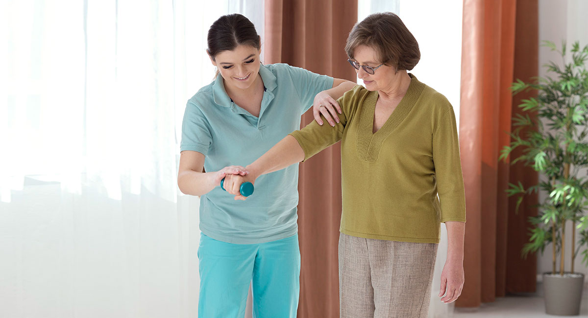 A homecare employee assists an elderly man in drinking water.