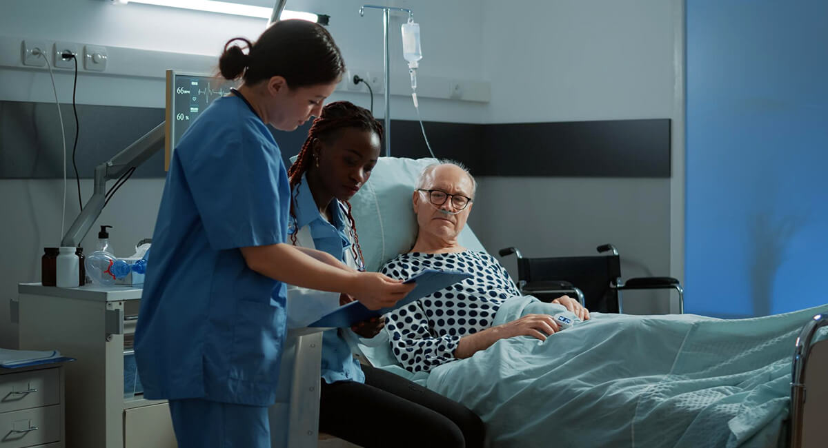 A patient is surrounded by carers providing end of life care service.