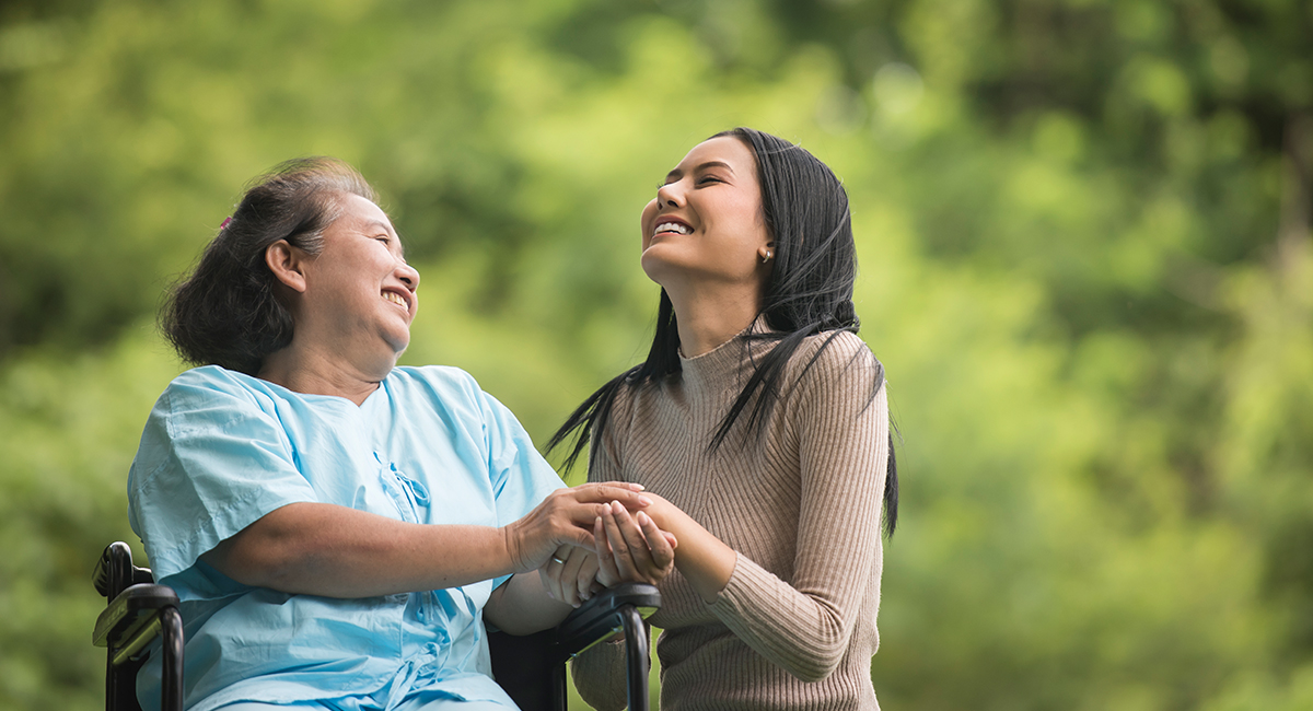 A carer offers companionship to an elderly woman in a wheelchair