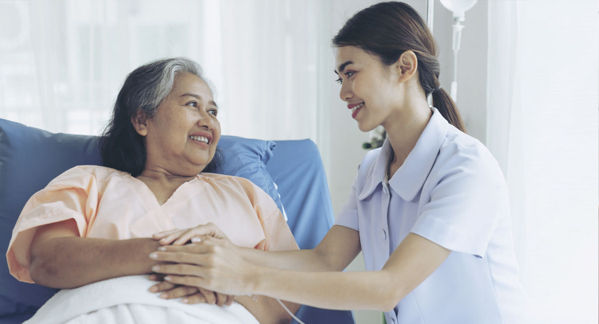 A kind support worker providing care to an old lady in bed