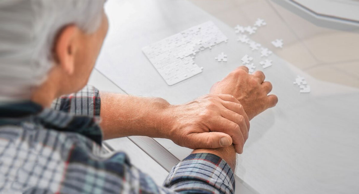 A senior citizen tightly gripping his hand to prevent tremors.