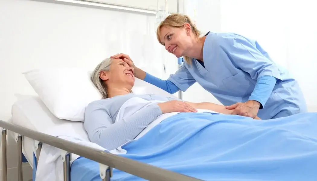 A care worker providing emotional support to a bedridden elderly person
