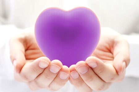 A purple heart inside a person's palm, providing a sense of security